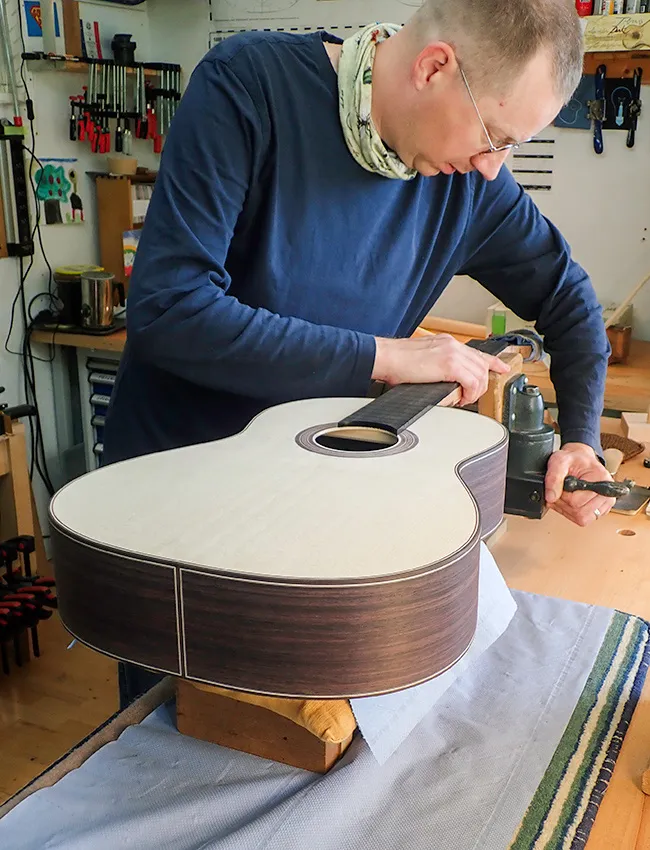 En gitarrmakare jobbar på en ny gitarr i en verkstad